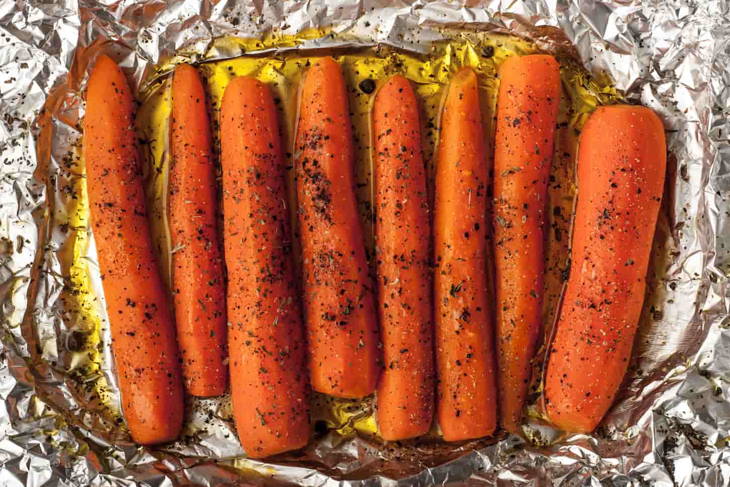 An image of Baked carrots with black pepper on a sheet of foil top view.