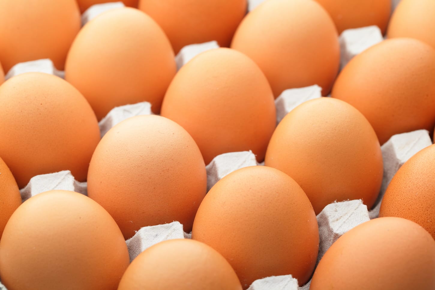 A close-up of raw farm brown eggs in egg tray.