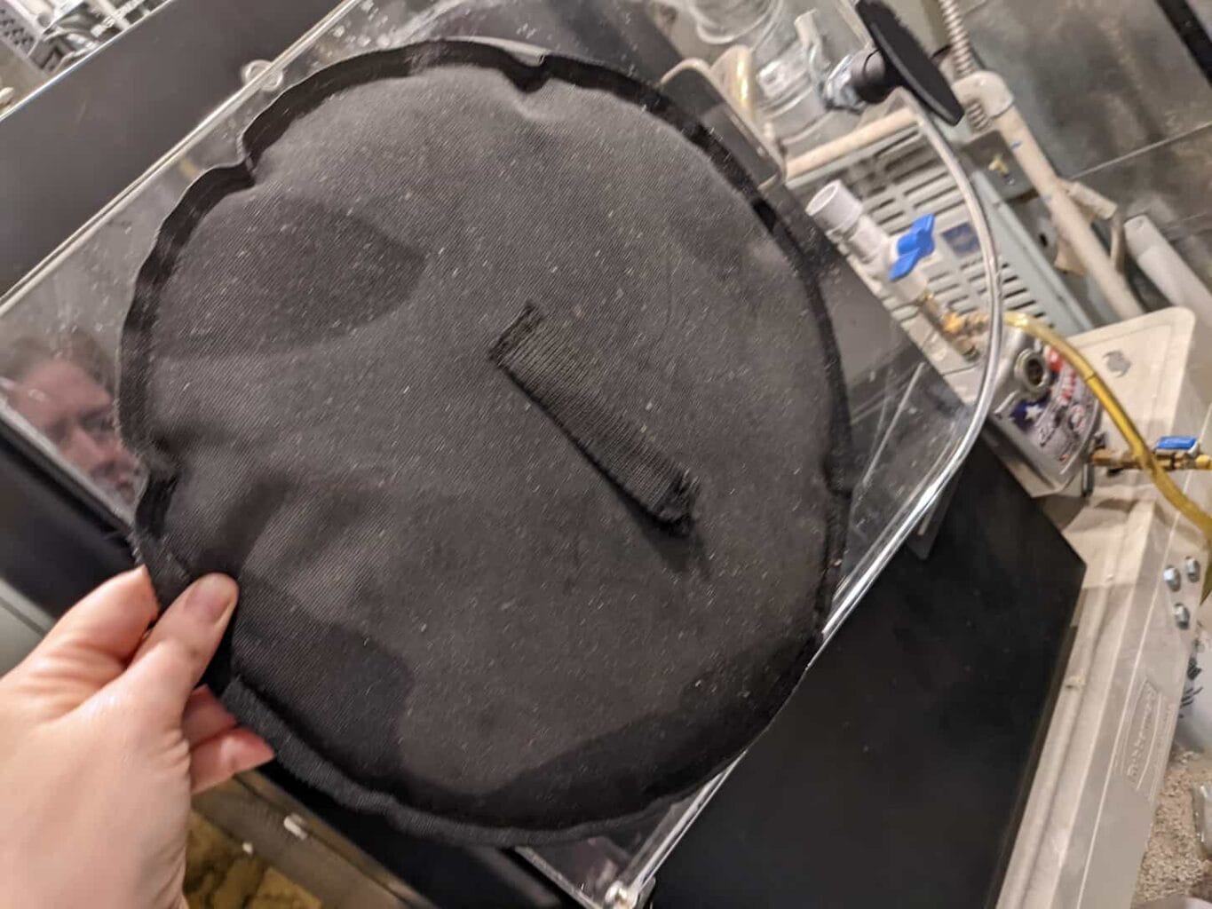 An image of a hand holding a black freeze dryer door pad.