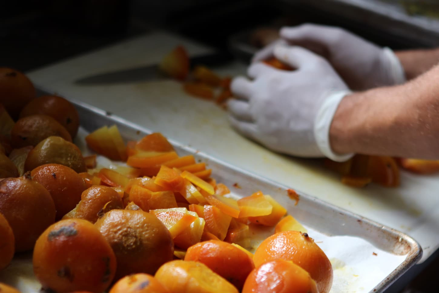 An image of a man's hands with sliced beets in a tray.