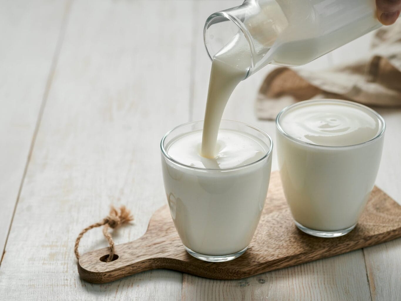 An image of a glass being poured with homemade kefir, buttermilk, or yogurt with probiotics.