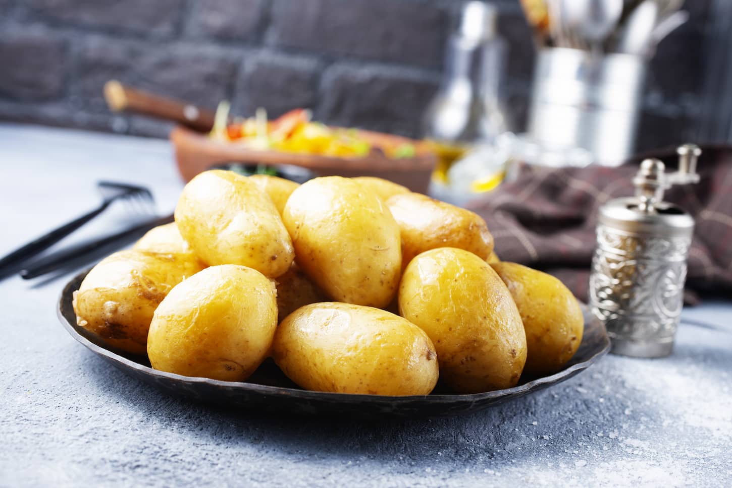 An image of boiled potatoes on a black plate.