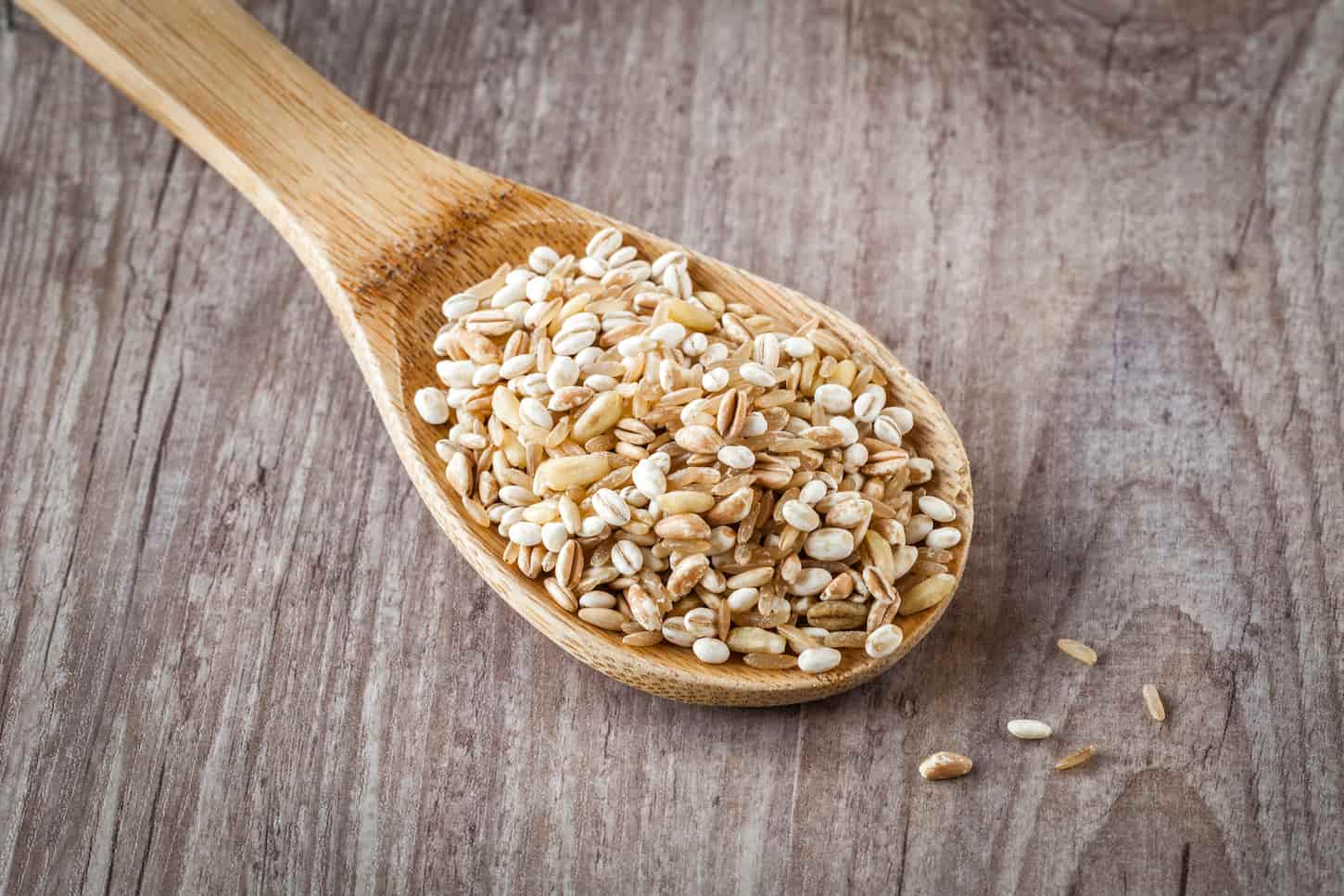 An image of Mixed raw cereals on a wooden spoon.