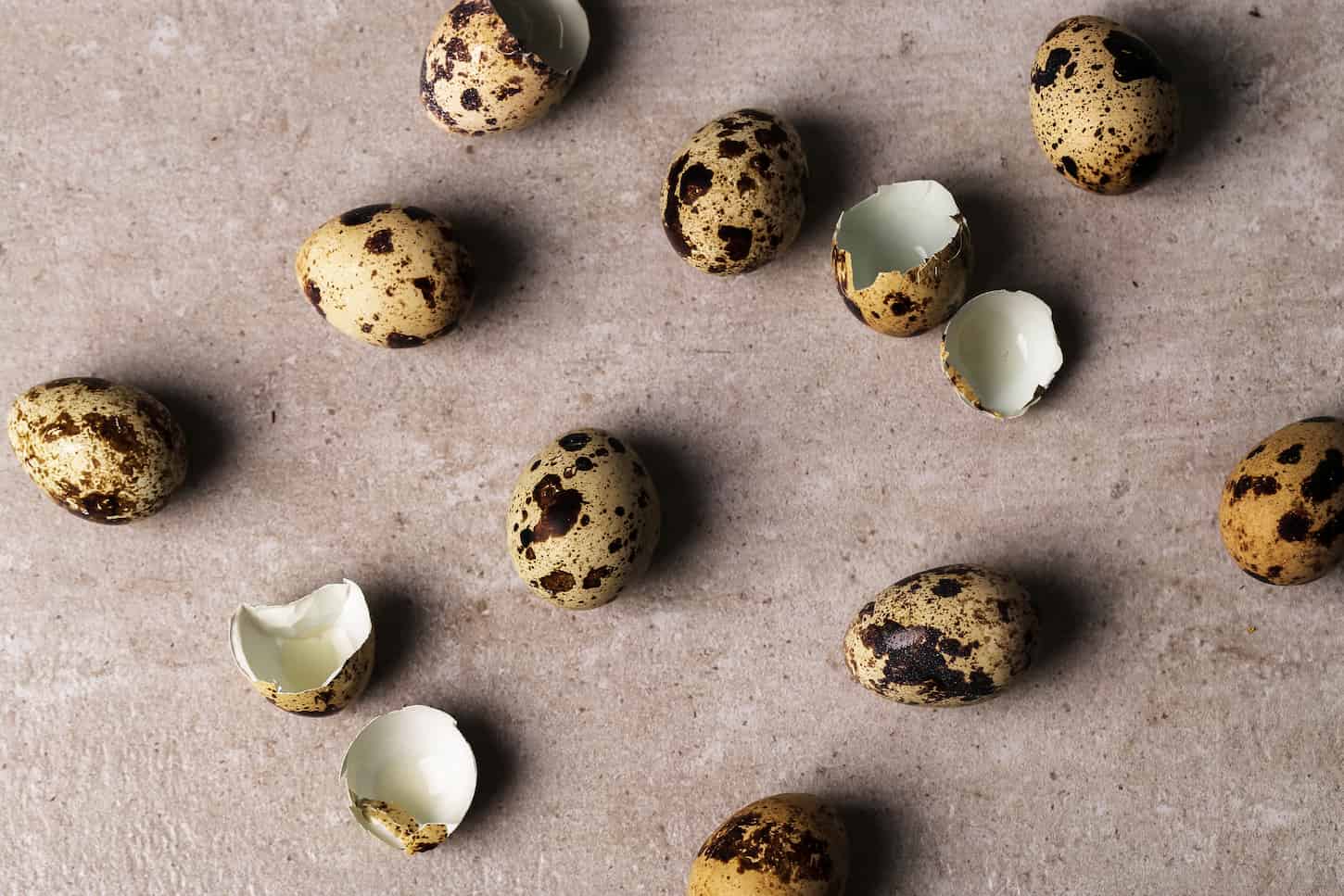 An image of quail eggshells scattered on a marble table.