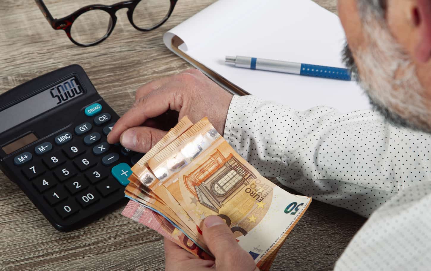 An image of a man calculating monthly costs and expenses.