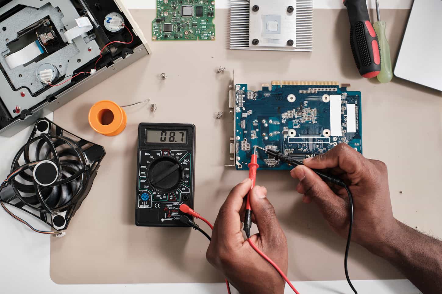 An image of a Layout of the hands of a repairman soldering tiny details on a circuit board.
