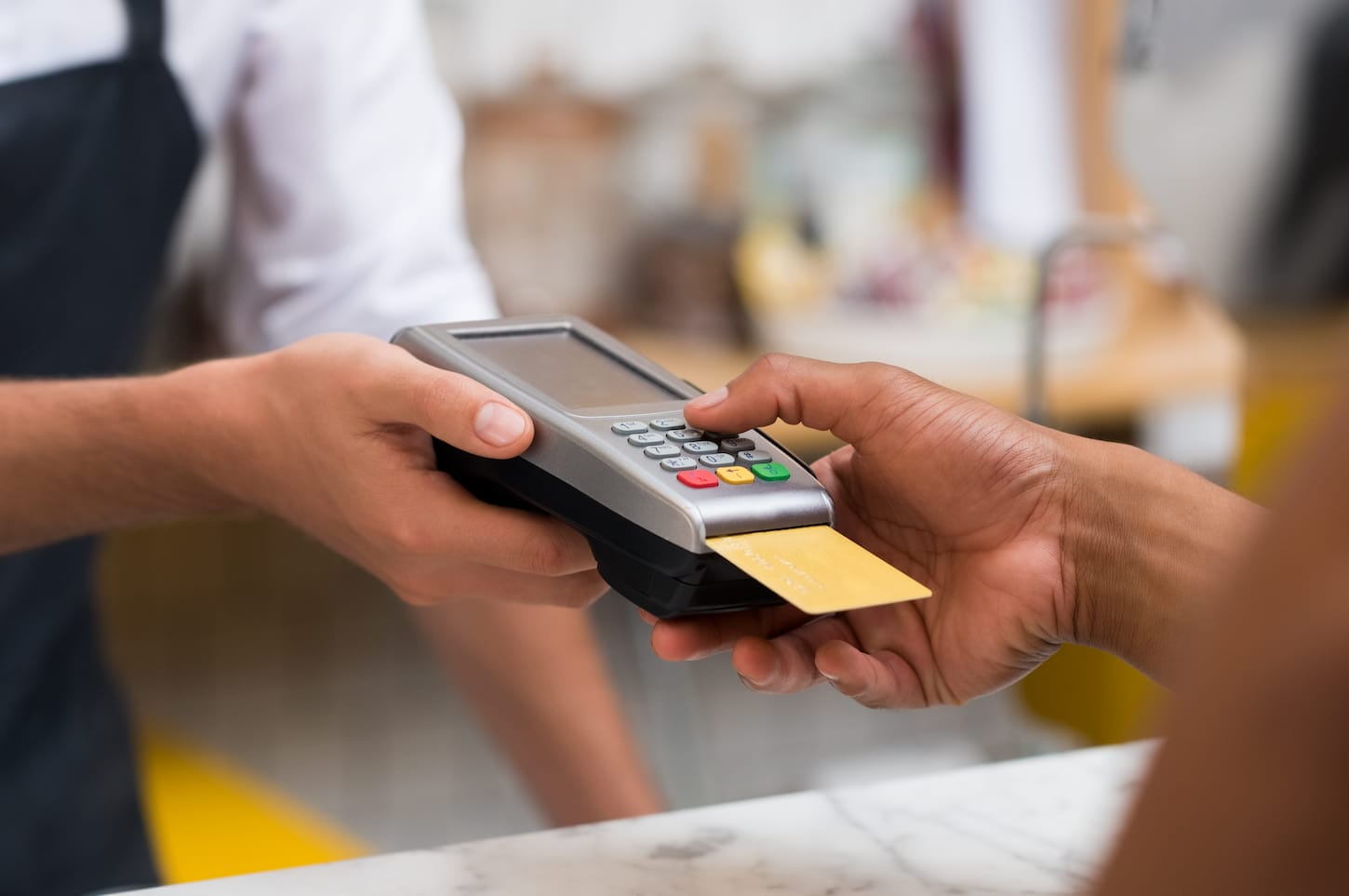 An image of a hand using a credit card swiping machine to pay. 