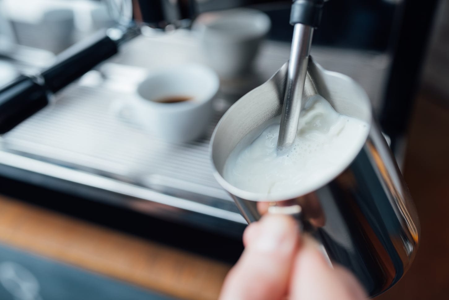 An image of steam frothing milk under pressure from a coffee machine in the pitcher.