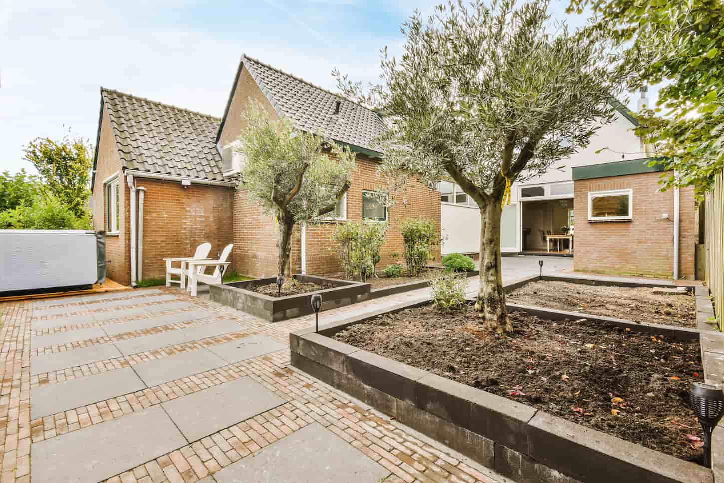 An image of The backyard of the house with a garden and trees.