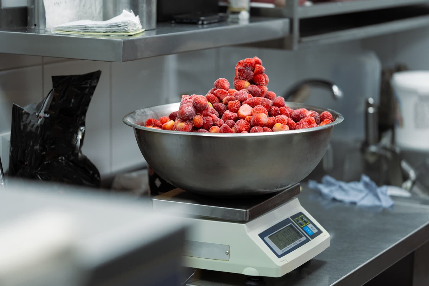 An image of Frozen berries in a bowl on a culinary scale.