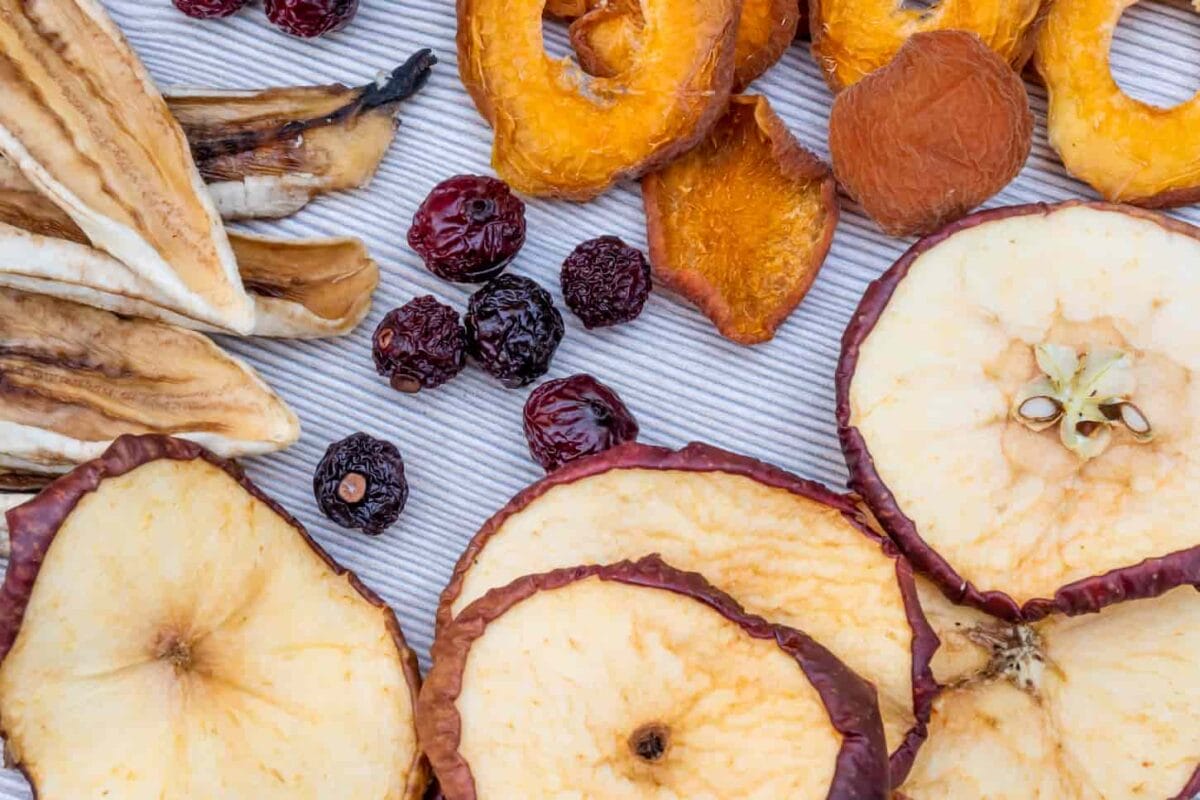 An image of Sliced dried dehydrated fruits and berries on a light table. The concept of home preparation of dried fruits in a dehydrator.