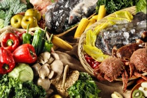 An image of various fresh foods including sea food, fruits, and vegetables.